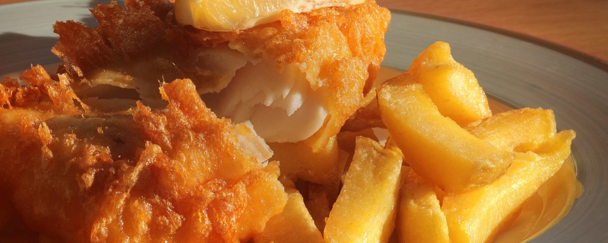 Close-up of golden battered fish with fluffy chips on a plate